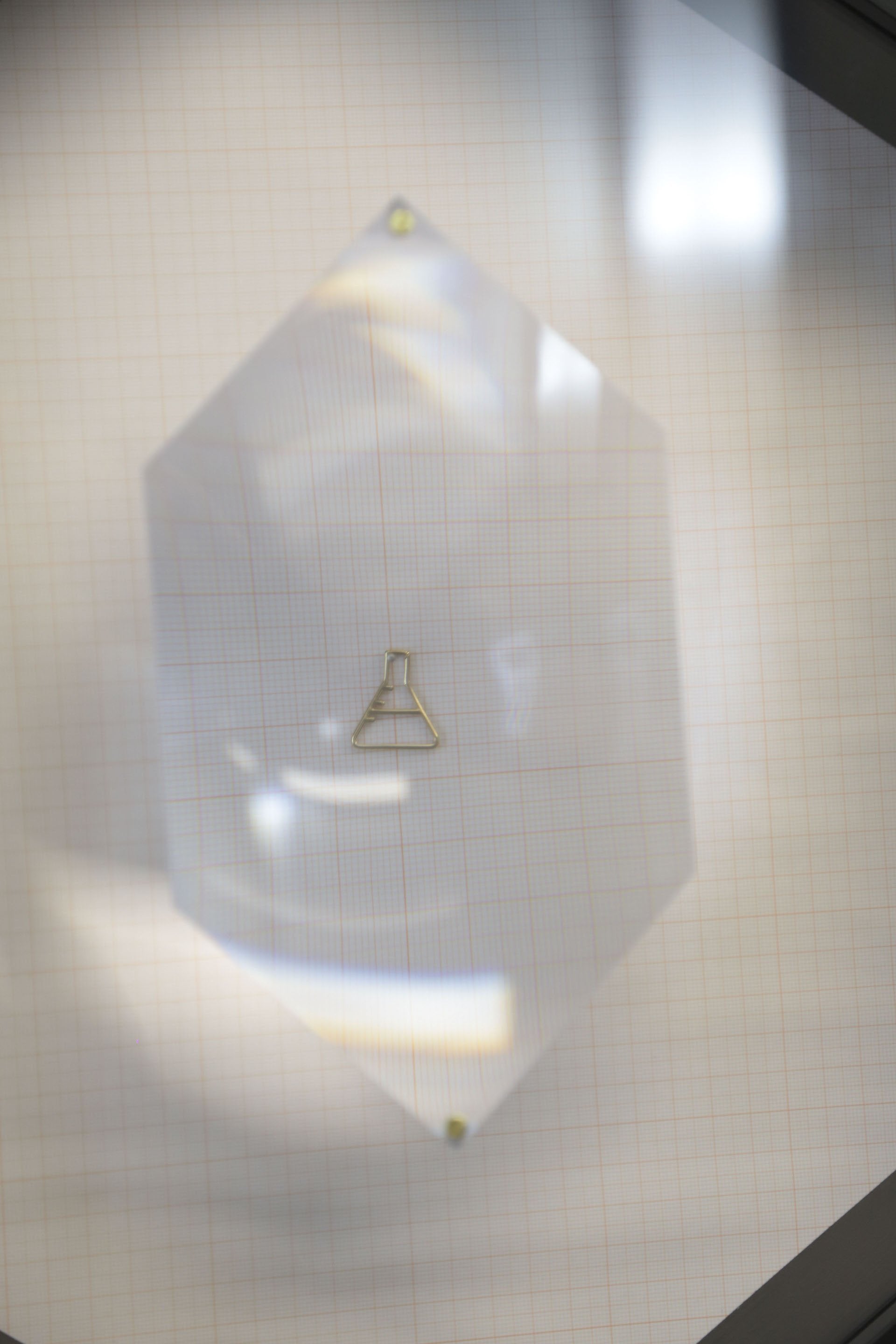 Gold chain necklace with chemistry baker shaped pendant under lens