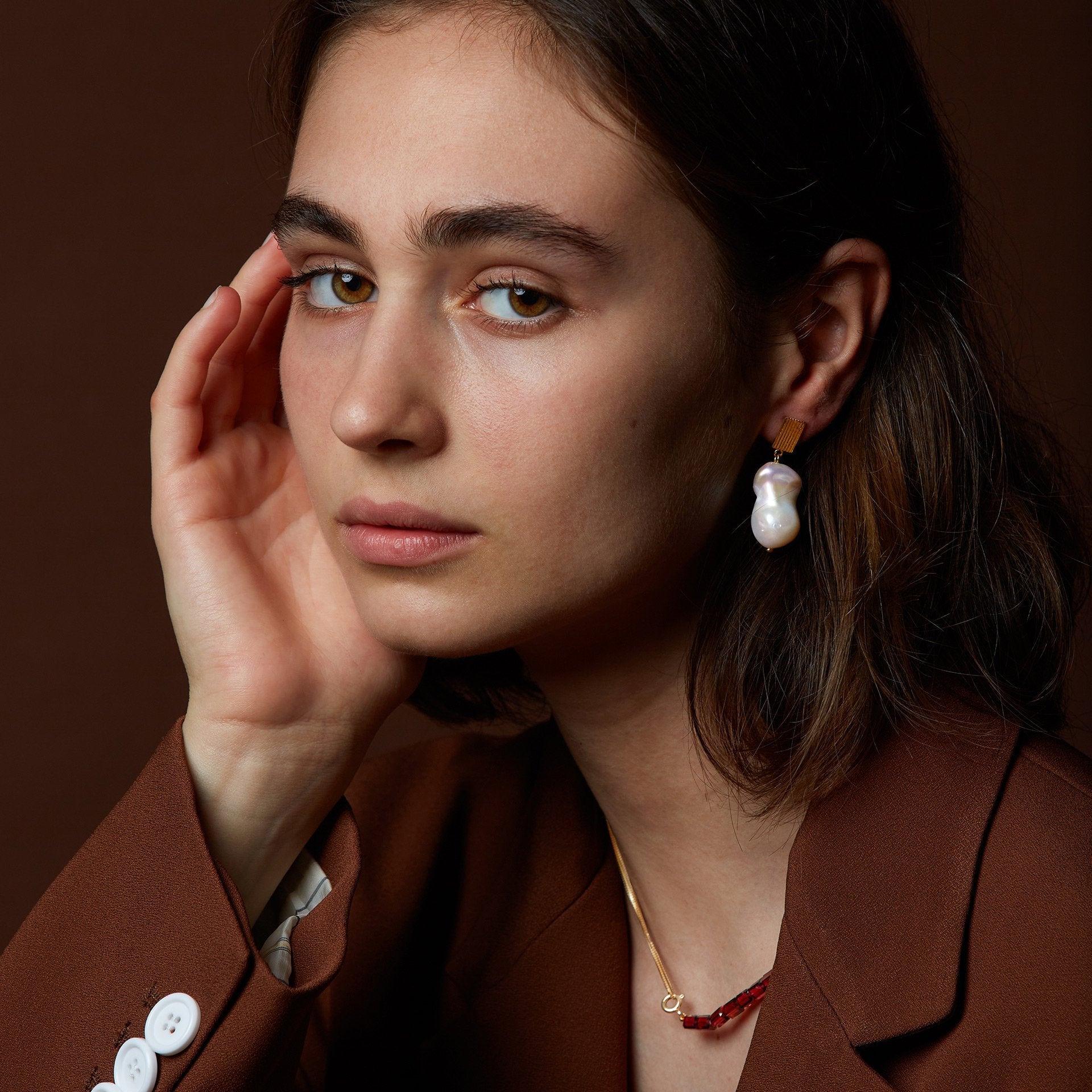Model wearing gold earring with fresh water baroque pearl