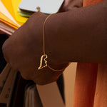 Gold chain bracelet with dinosaur shaped pendant worn by model