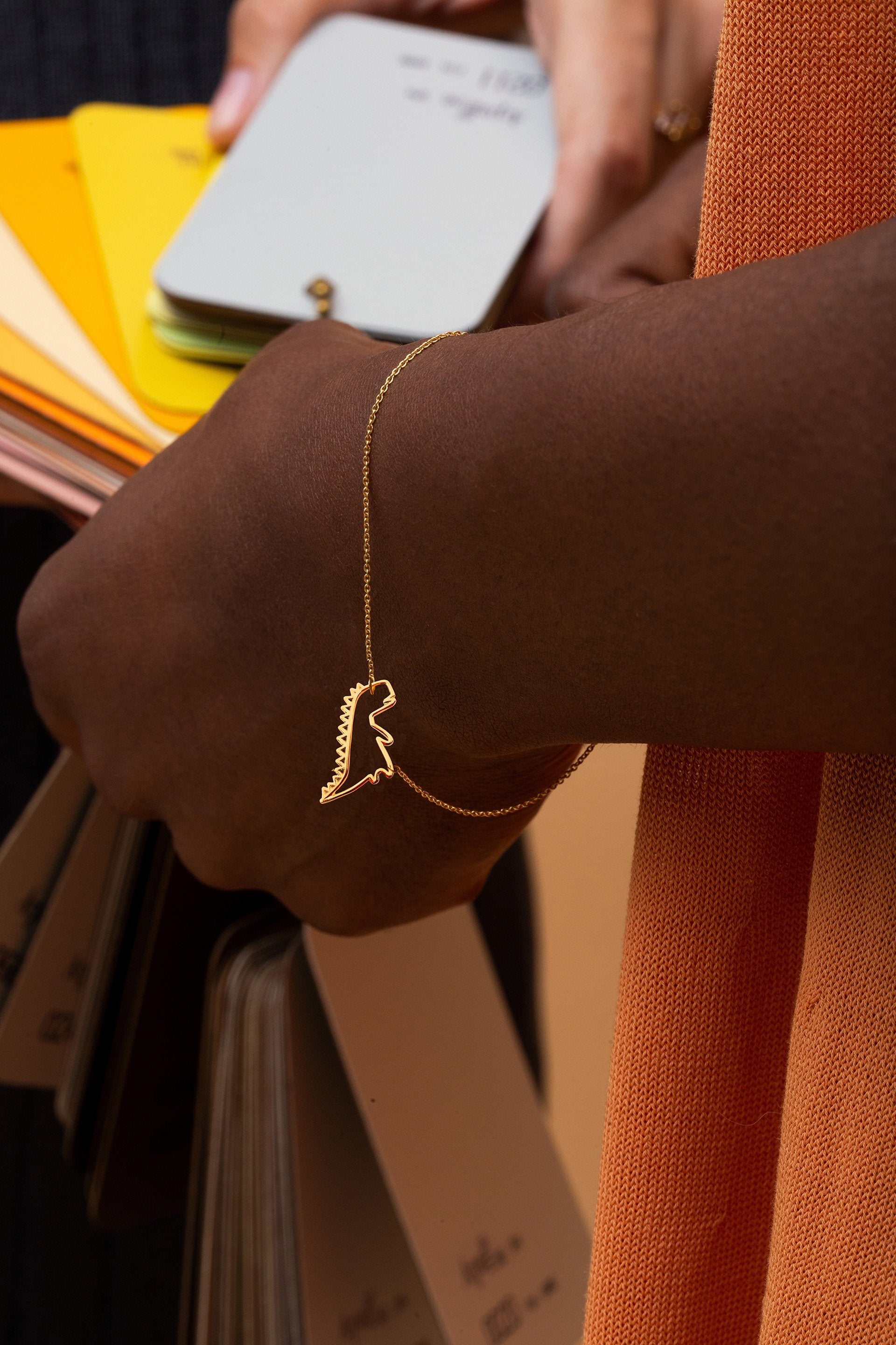 Gold chain bracelet with dinosaur shaped pendant worn by model