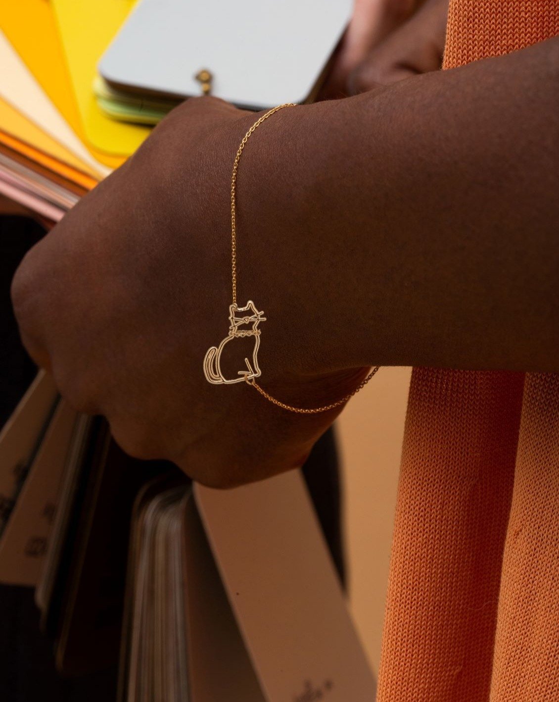 Gold chain bracelet with seated cat shaped pendant worn by model