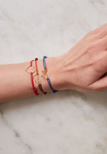 Load image into Gallery viewer, Model&#39;s wrist wearing colored cord bracelets with small heart and rabbit shaped pendants
