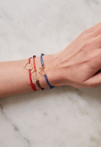 Model's wrist wearing colored cord bracelets with small heart and rabbit shaped pendants