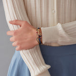 Bottle green cord bracelet with pink tennis racquet shaped gold pendant  worn by model