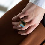 Gold square rings with jasper stone and blue jade worn by model
