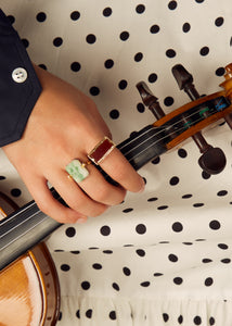 Hand holding violin wearing gold rings with hard stones