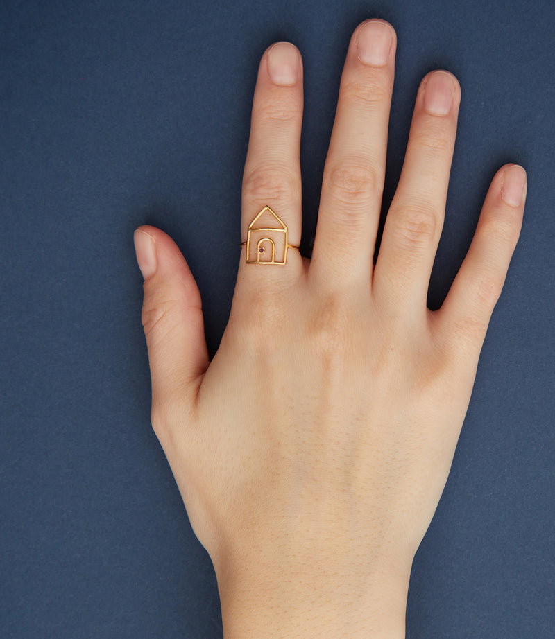 House shaped gold ring with small ruby on model's hand