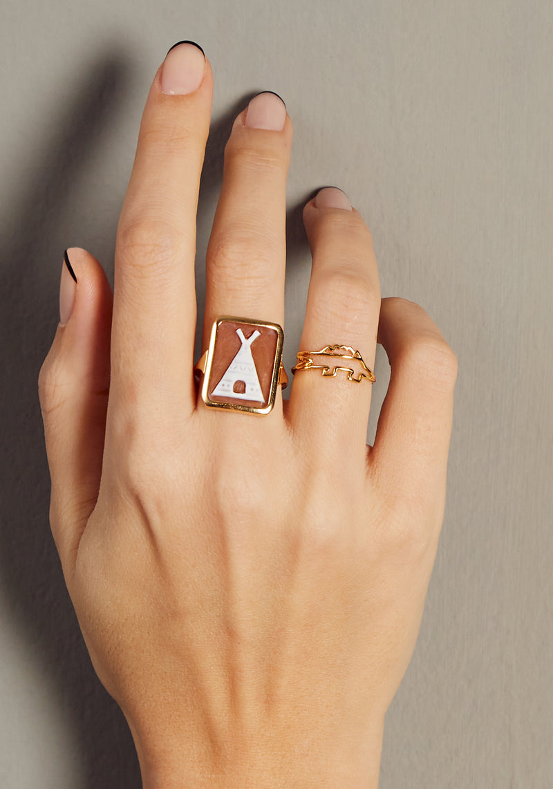 Hand wearing a cameo on shell gold ring and a crocodile shaped gold ring