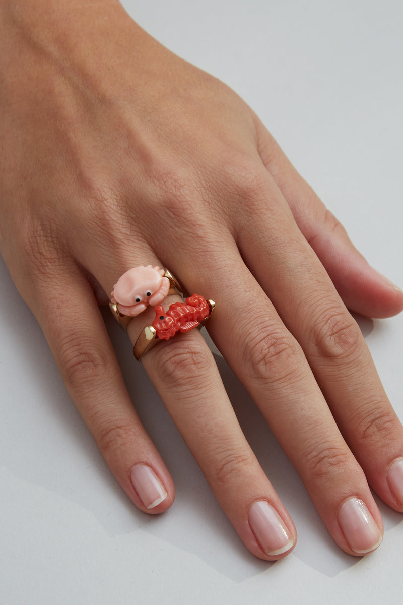 Gold rings with seahorse and crab shaped coral on model's hand