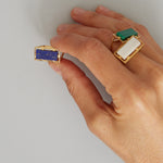 Hand with gold rings with lapis and white agate stones