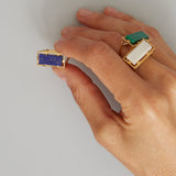 Hand with gold rings with lapis and white agate stones