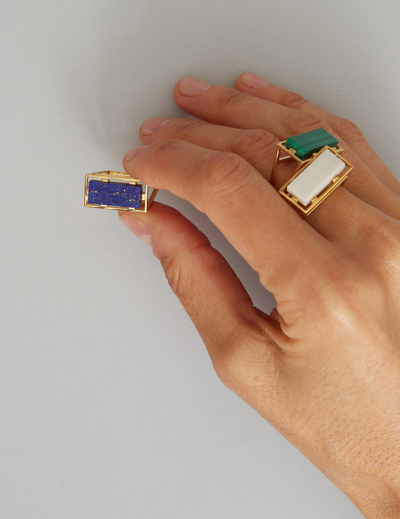 Hand with gold rings with lapis and white agate stones