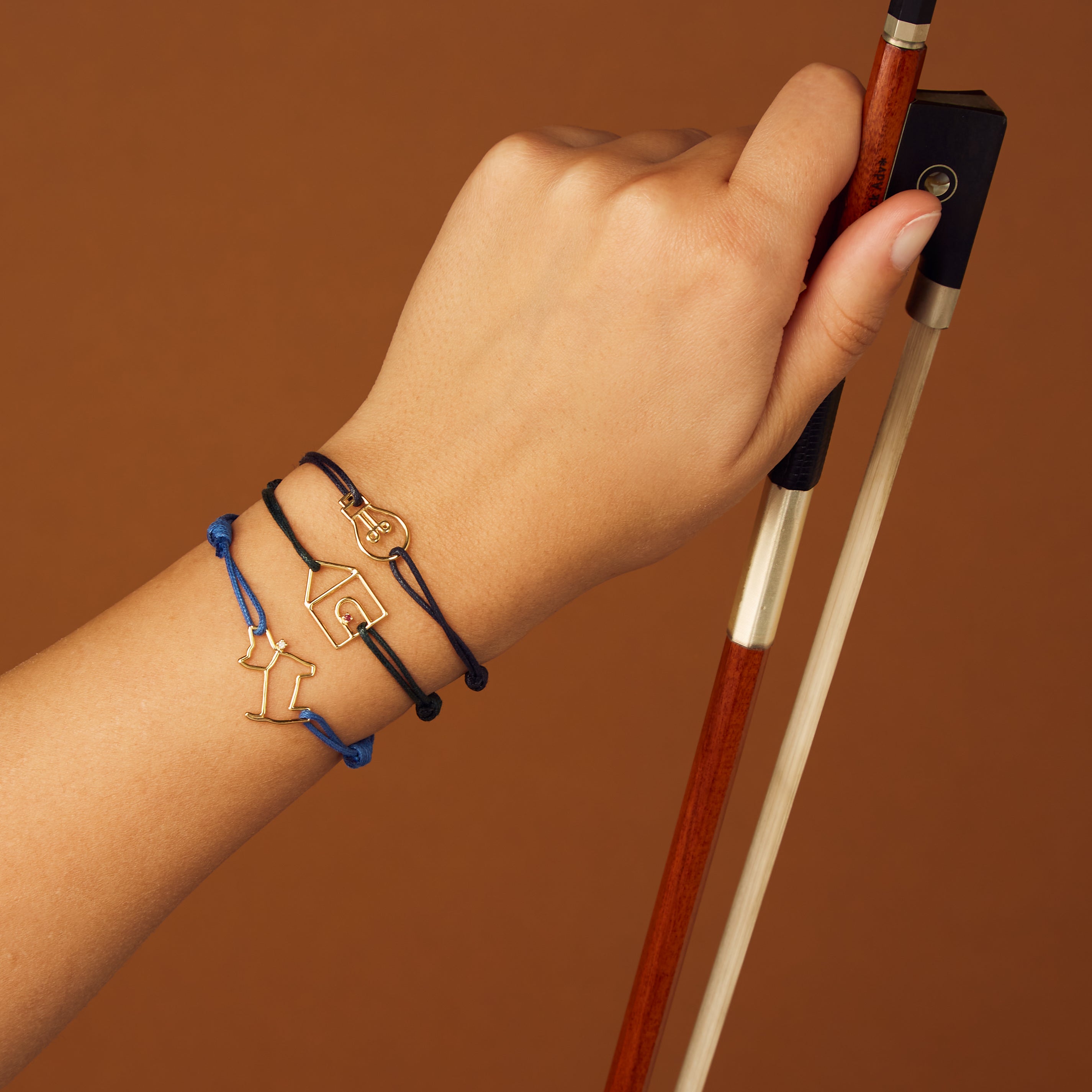 Blue cord bracelet with gold dog shaped pendant and small diamond worn by model