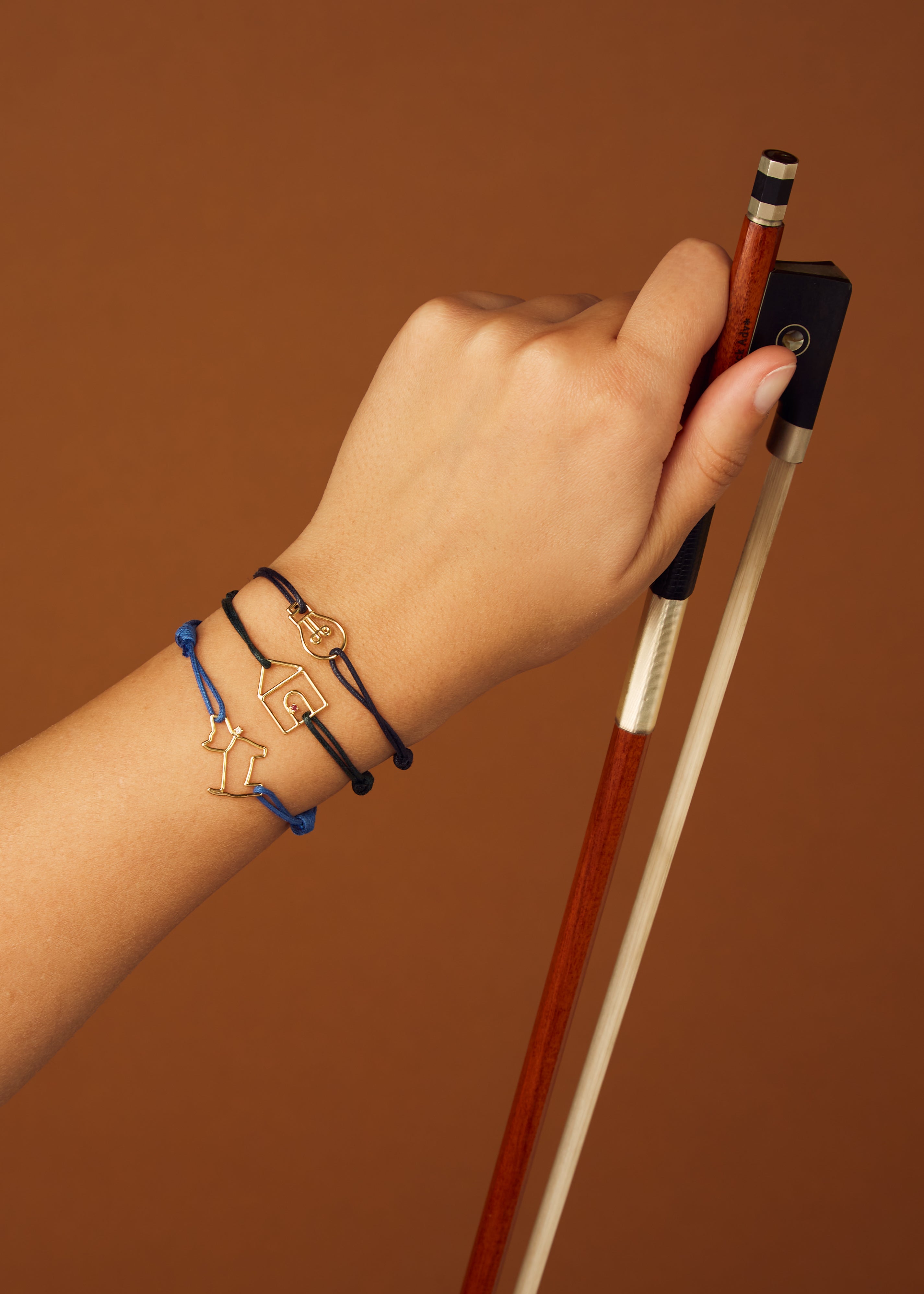 Blue cord bracelet with gold dog shaped pendant and small diamond worn by model