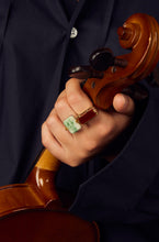 Load image into Gallery viewer, Hand holding violin wearing gold rings with stones
