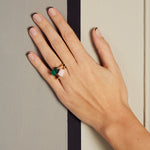 Hand wearing two gold rings with cylinder cut pink opal and malachite stones