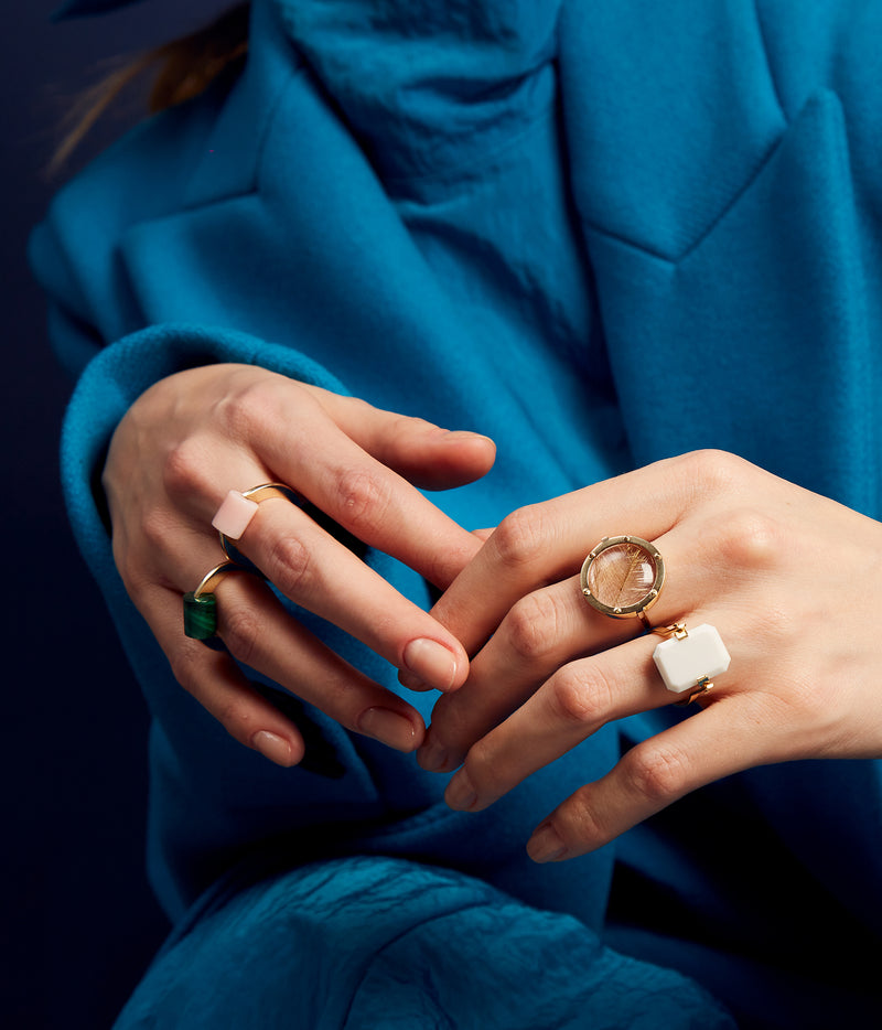 Hands wearing Aliita gold rings with natural stones
