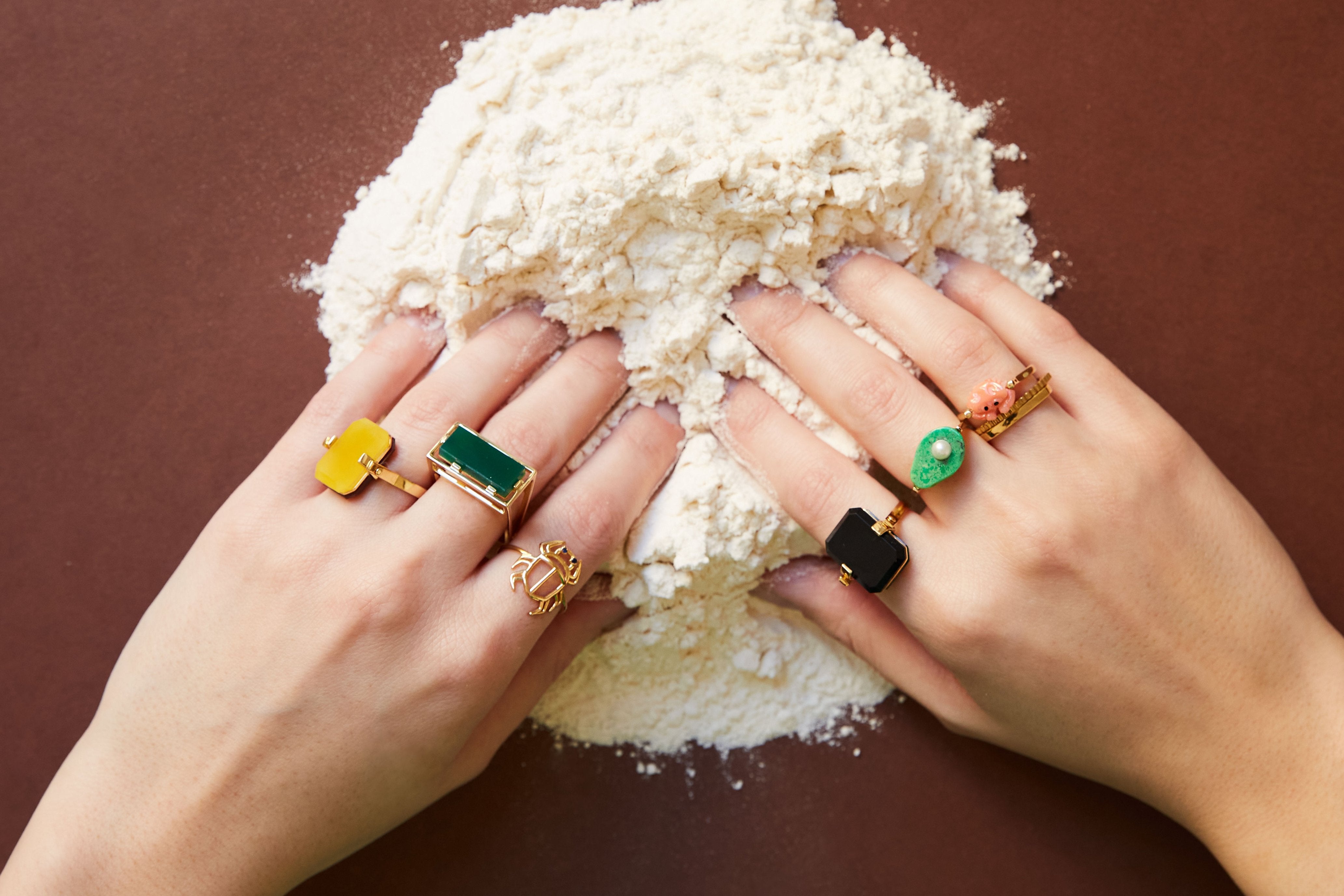 Hands dipped in flour wearing gold rings with precious stones 