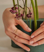 Load image into Gallery viewer, Hand with flowers wearing a gold ring shaped like a turtle with a green emerald eye
