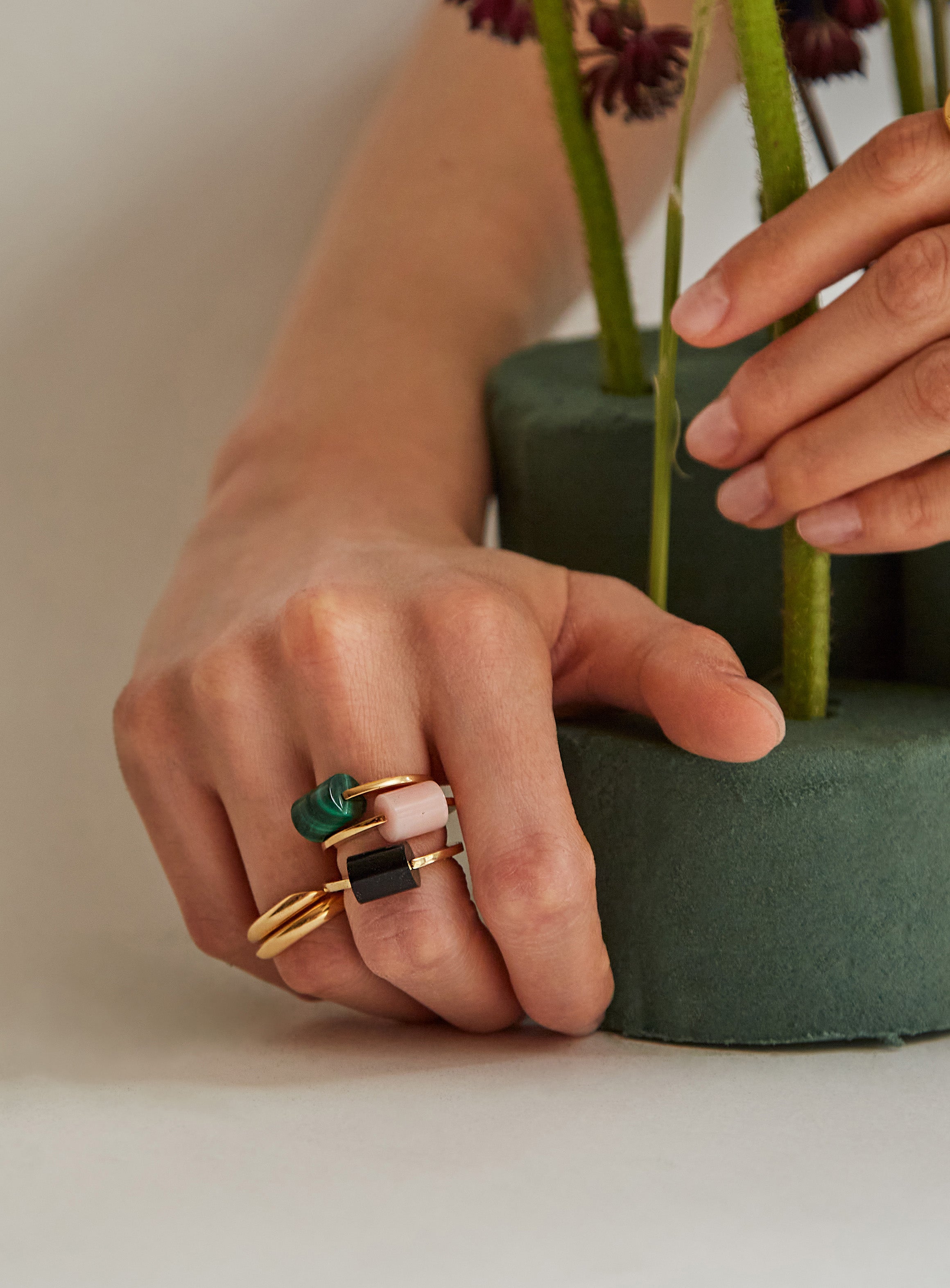 Hands wearing gold rings with precious stones
