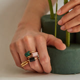 Hands wearing gold rings with precious stones