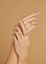 Load image into Gallery viewer, Hands wearing gold rings and with pink coral
