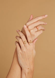 Hands wearing gold rings and with pink coral