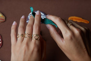 Gold rings shaped in cat, camera, shark with small diamonds on woman's hand