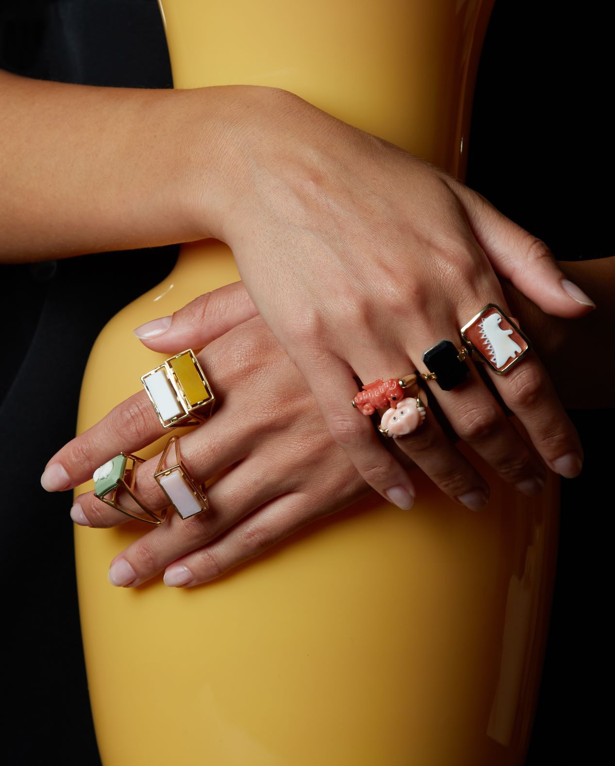 Hands holding vase wearing gold rings with precious stones