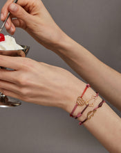 Load image into Gallery viewer, Hands holding an ice cream cup wearing cord bracelets with gold pendants
