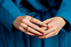 Woman wearing gold rings, with citrine stone and a watermelon slice in red coral
