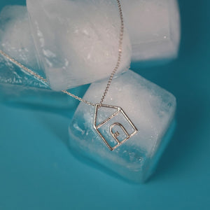 White gold chain necklace with house shaped pendant and small diamond on ice cubes