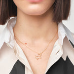 Model wearing gold chain necklace with small dog shaped pendant