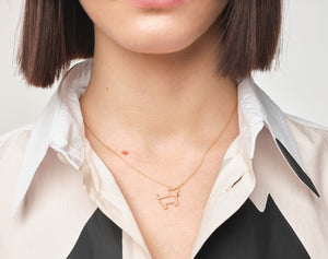 Model wearing gold chain necklace with small dog shaped pendant