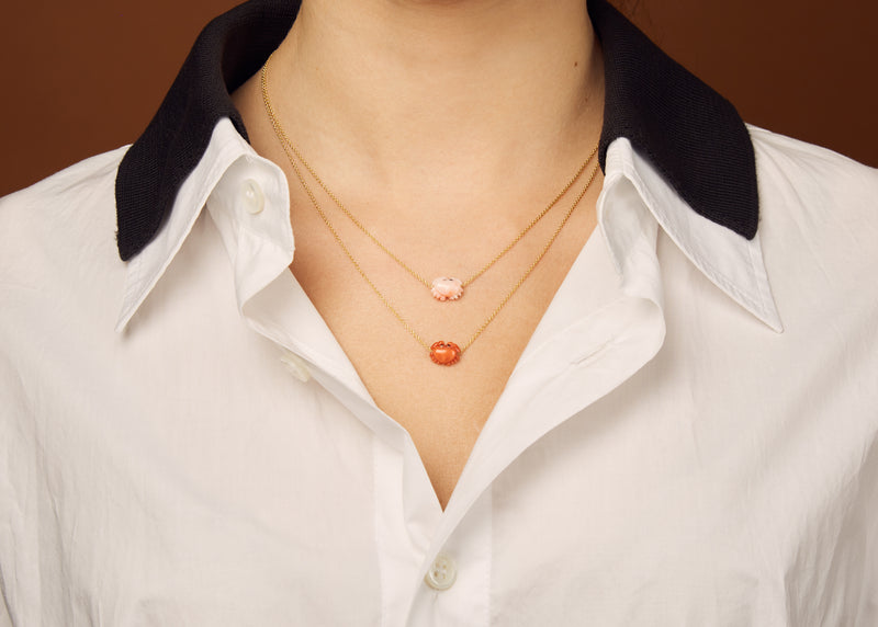 Gold chain necklace with mini pink crab shaped coral pendant worn by model