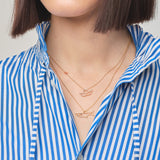 Model wearing gold chain necklaces with little boat and shark shaped pendantsGold chain necklace with shark shaped pendant with blue sapphire eye worn by model