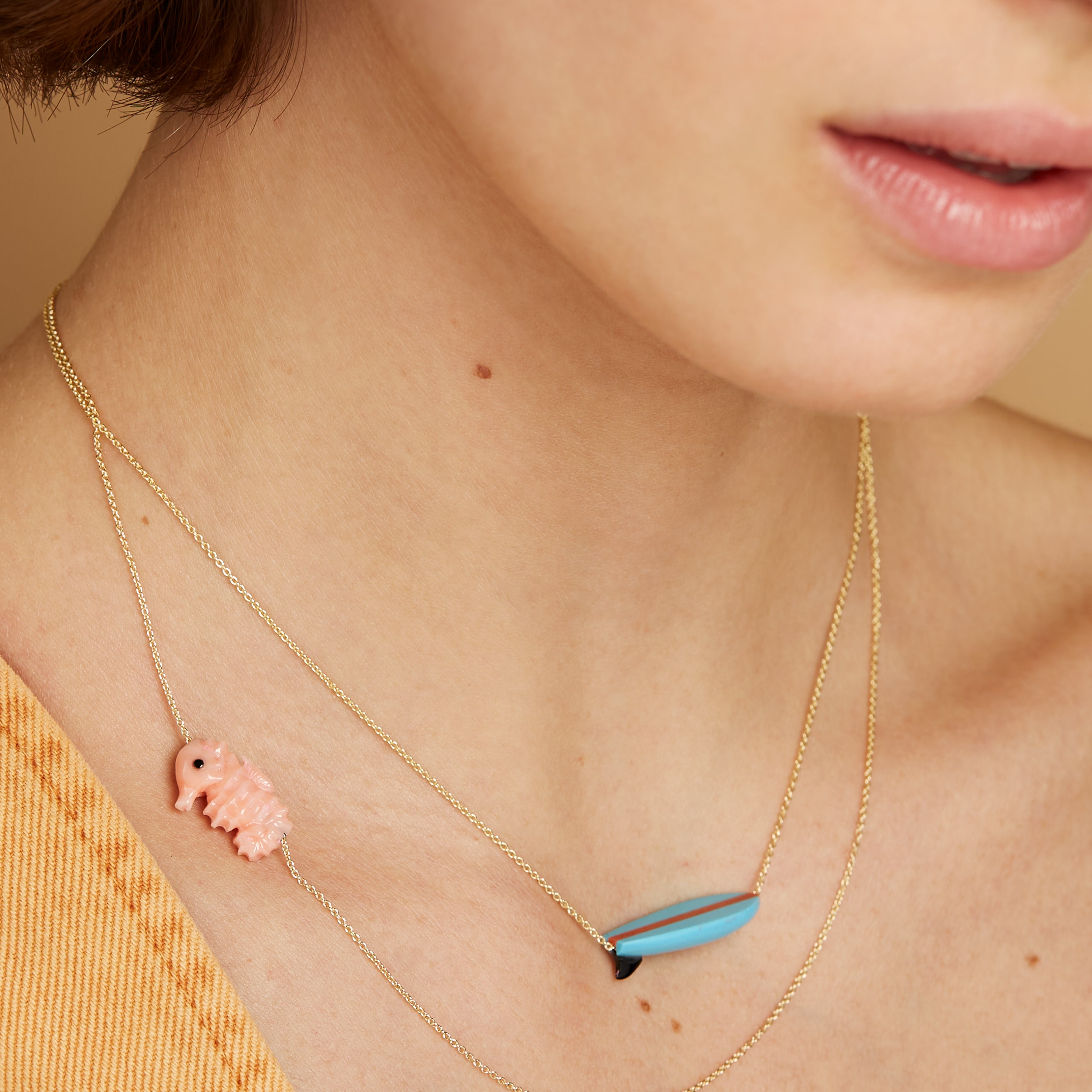Gold chain necklace wih surf shaped turquoise pendant worn by model