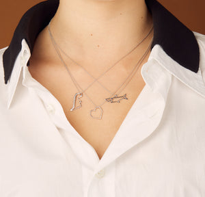 Model wearing White gold chain necklaces with dinosaur, heart, shark shaped pendants 