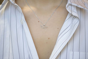 White gold chain necklace with little boat shaped pendant worn by model