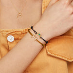 Model wearing cord bracelets and necklace with gold croissant shaped pendants