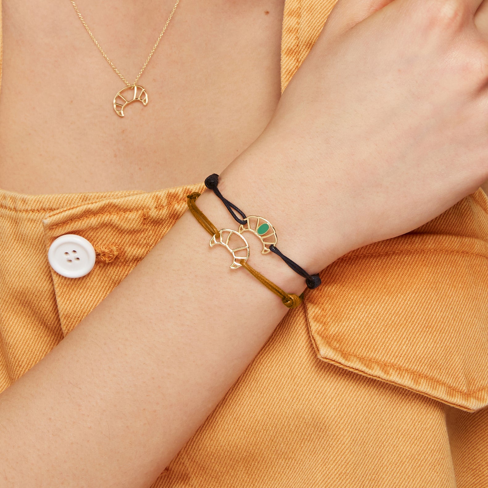 Model wearing cord bracelets and necklace with gold croissant shaped pendants