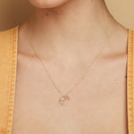 Gold chain necklace with small croissant shaped pendant worn by model