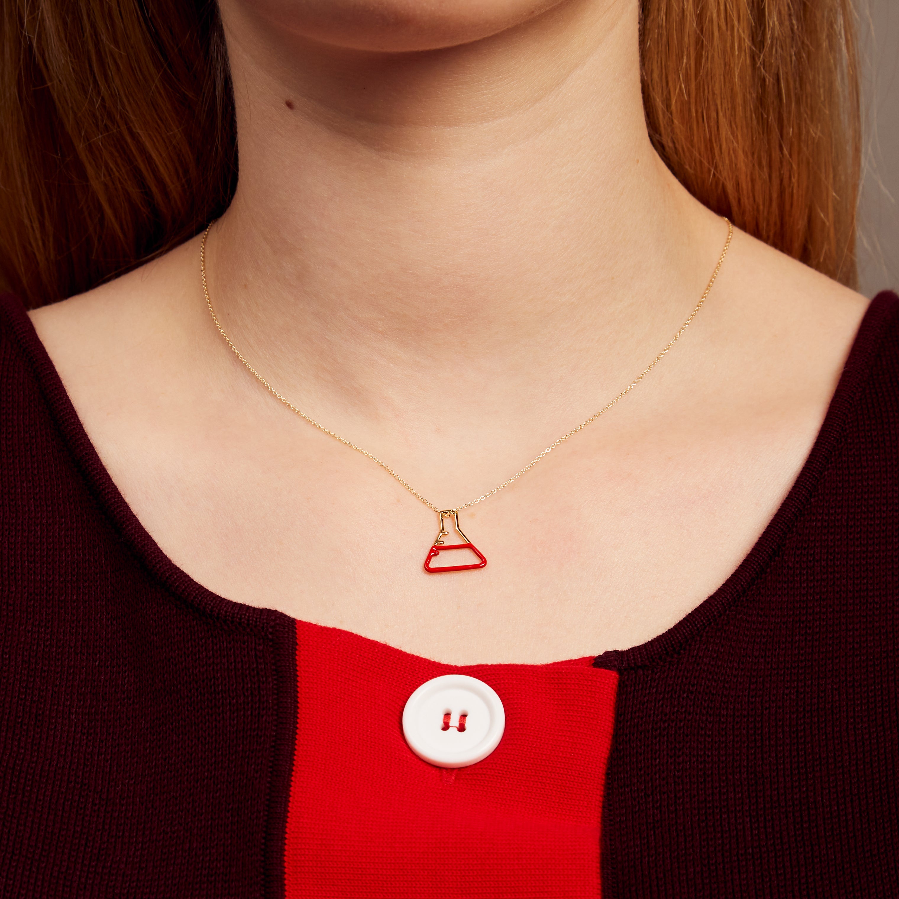 Gold chain necklace with small chemistry baker pendant hand-painted in red enamel on model