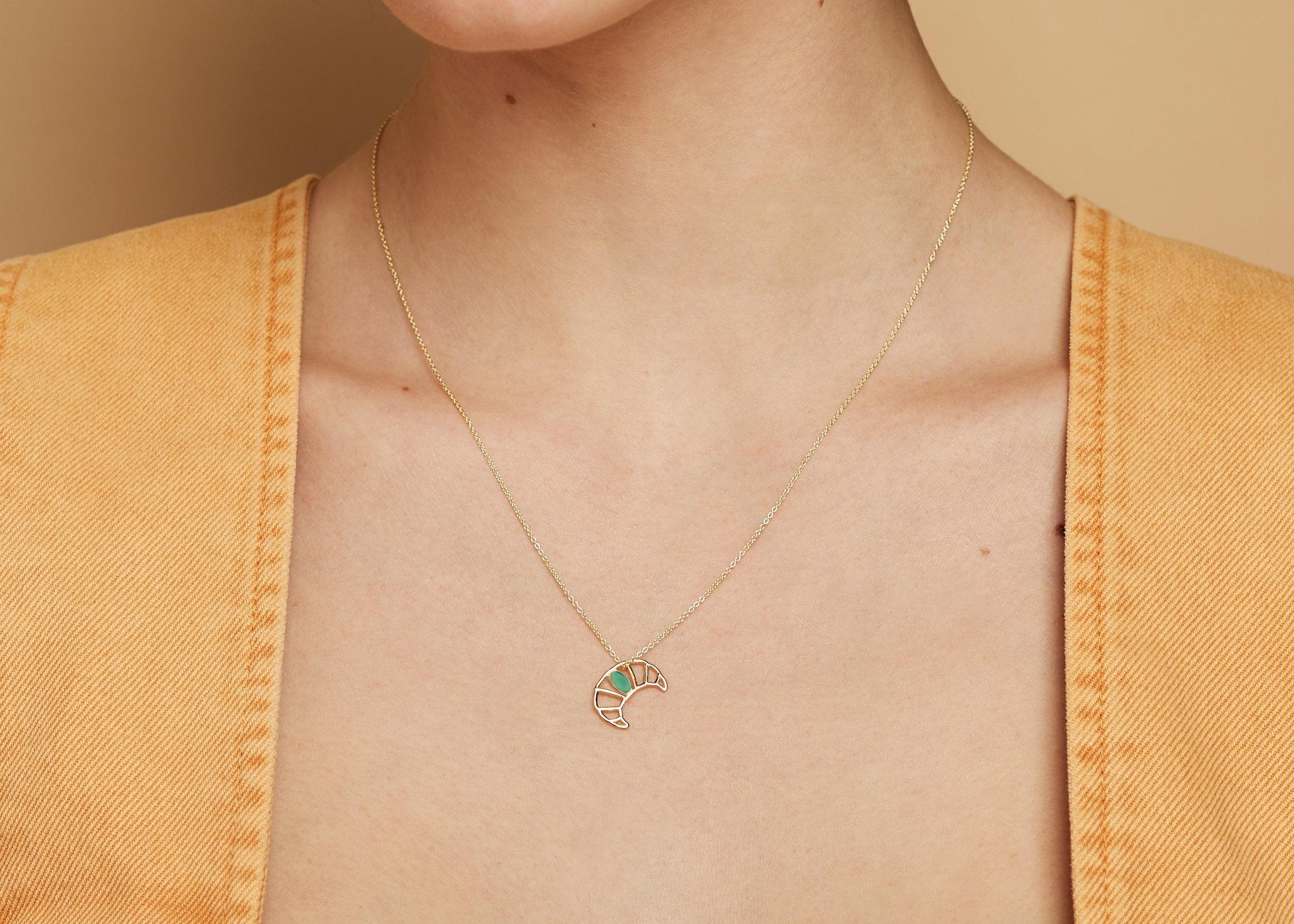 Gold chain necklace with croissant shaped pendant hand-painted in pistachio enamel worn by model