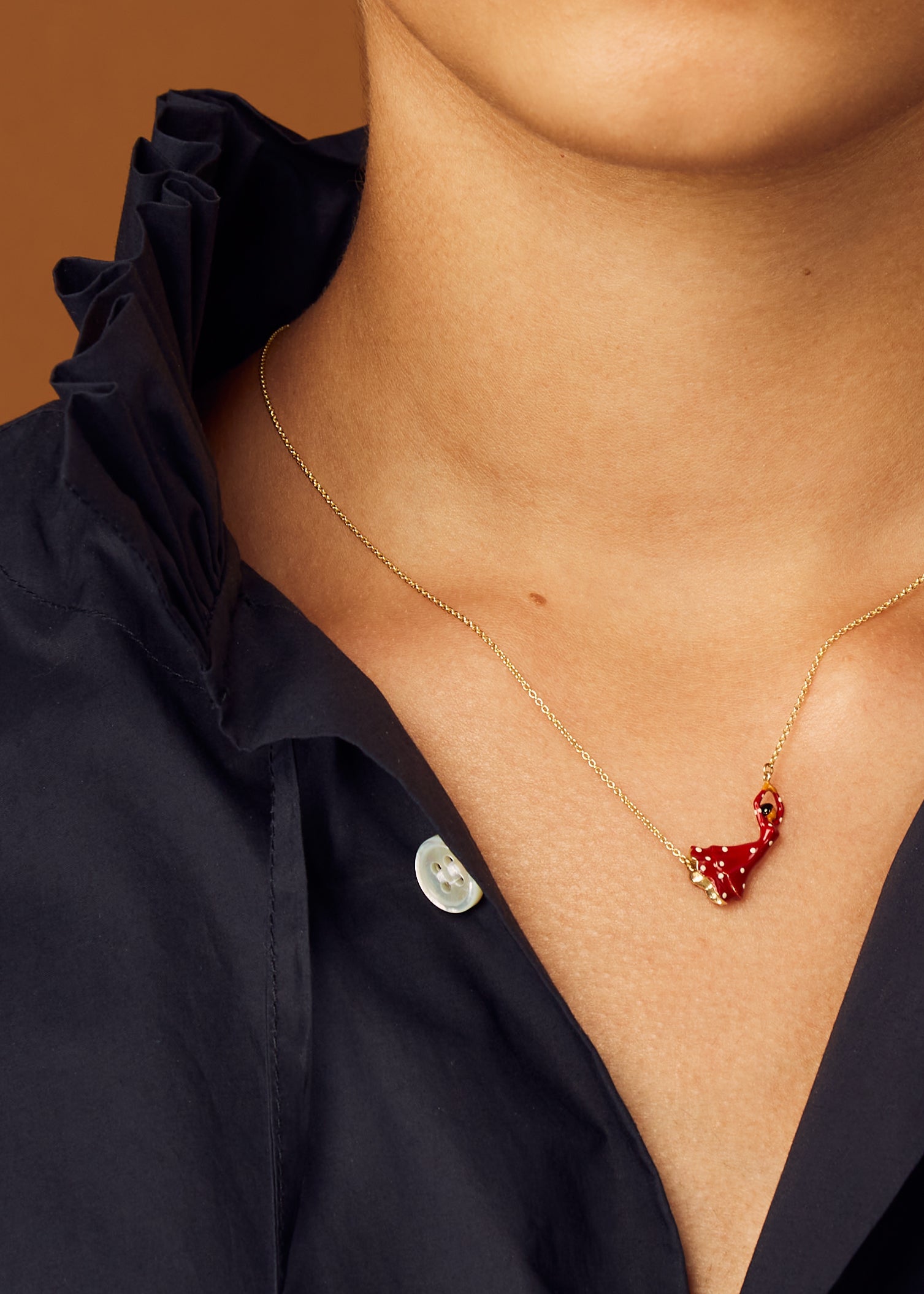 Gold chain necklace with flamenco dancer shaped pendant in red enamel worn by model