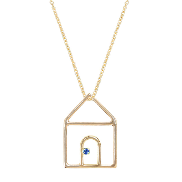 Gold chain necklace with house shaped pendant and small blue sapphire