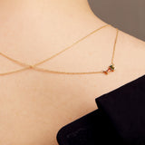 Gold rolo chain necklace with a baguett cut citrine and a baguette cut pink tourmaline on woman