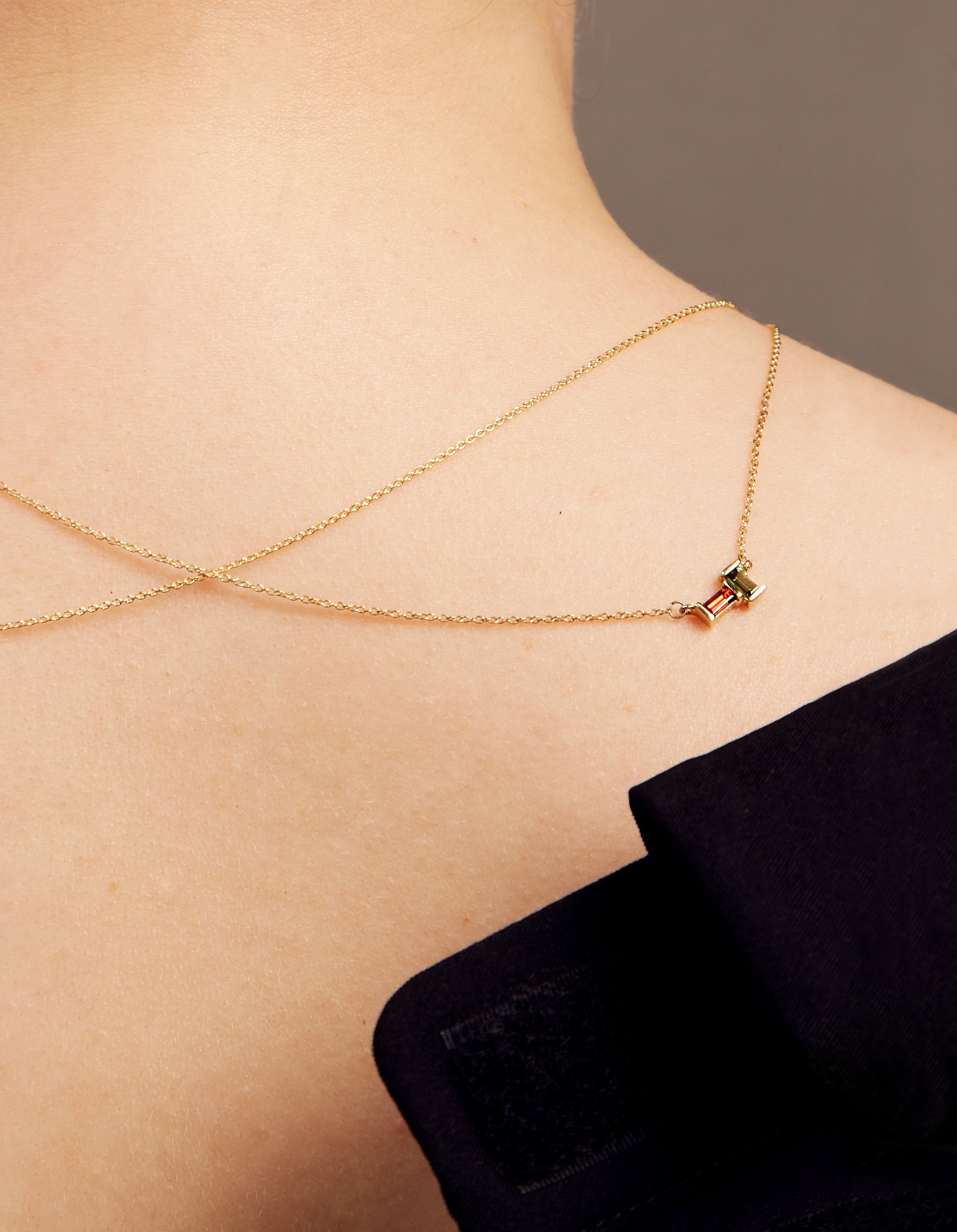 Gold rolo chain necklace with a baguett cut citrine and a baguette cut pink tourmaline on woman