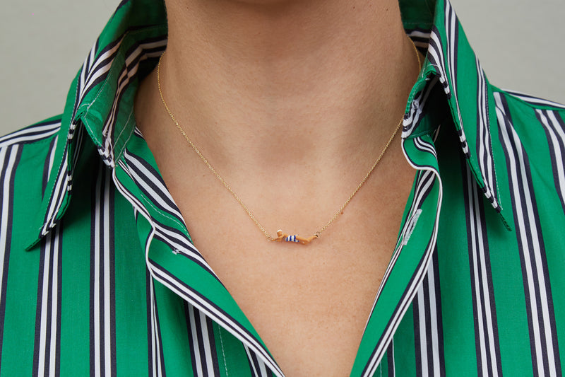 Gold chain necklace with swimmer shaped pendant with blue striped enamel swimsuit worn by model