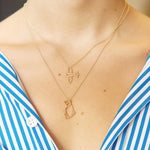 Gold chain necklaces with airplane and cat shaped pendants worn by model